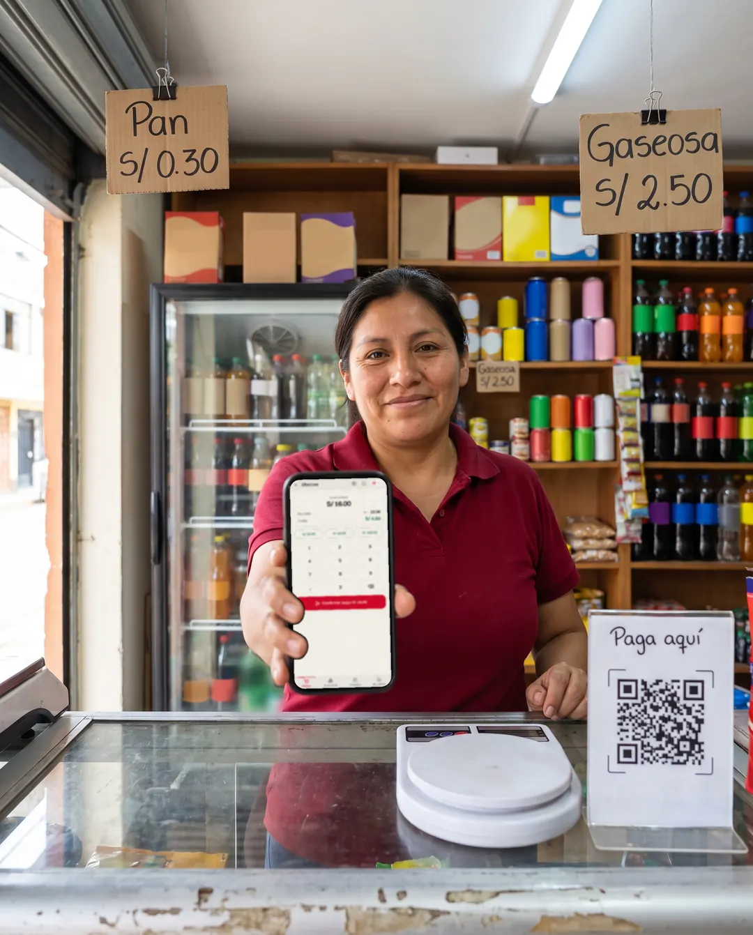 Dueña de un minimarket muestra Musuq en su celular desde el mostrador.